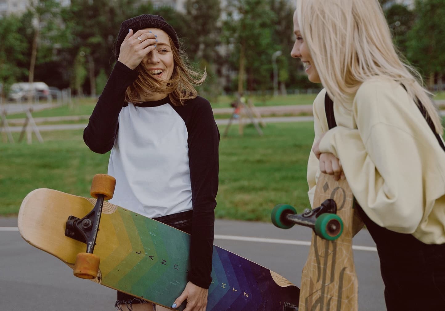 Две радостные девочки-подростки в парке со скейтами